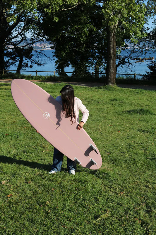 Antía con la tabla de surf de fibra flight mode rosa por la parte de detrás.