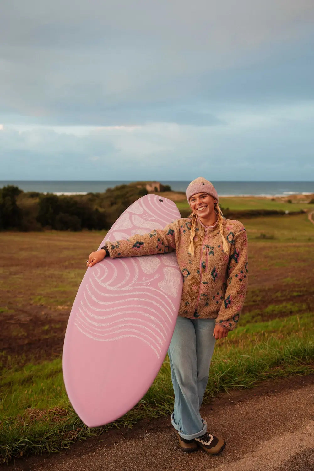 Chica con la tabla de fibra rosa con un diseño en la tabla hecho con cera.