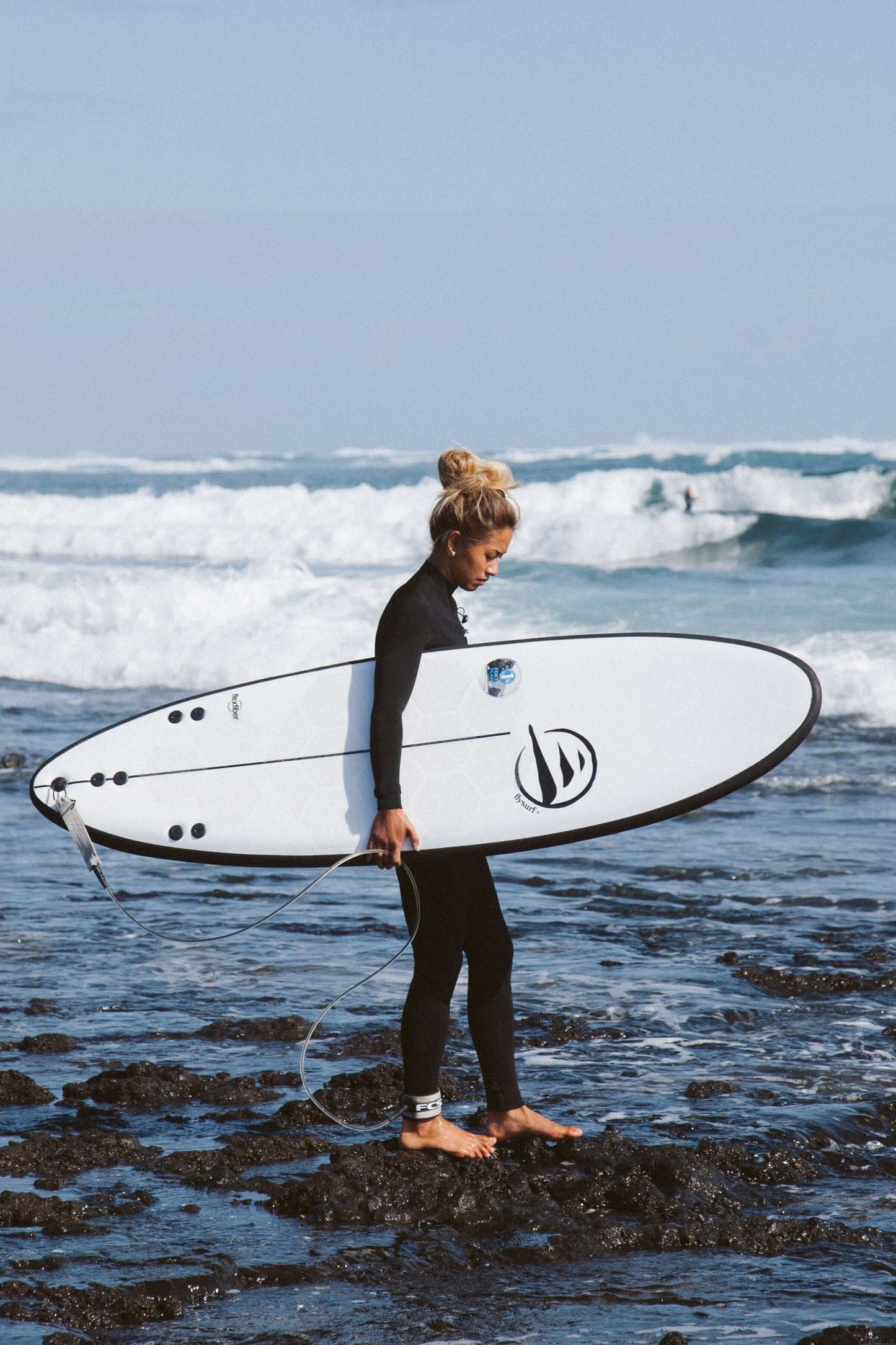 influencer andando por la playa con tabla de surf dharma de flysurf