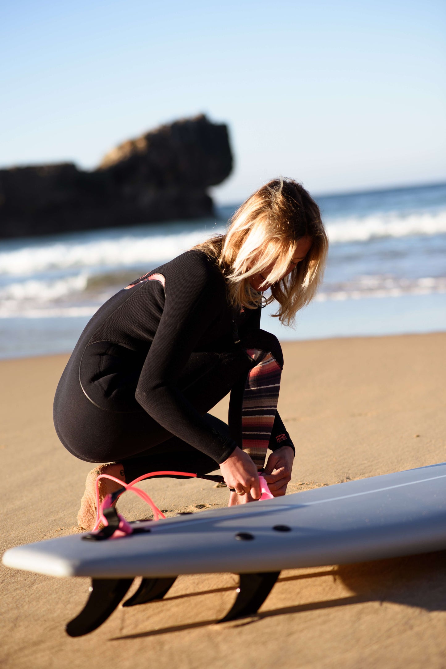 influencer poniendose un leash de flysurf en la playa antes de hacer surf