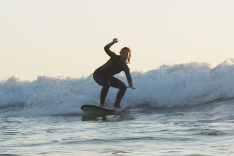 Persona poniendose de pie en tabla de surf siguiendo los mejores tips para progresar en surf