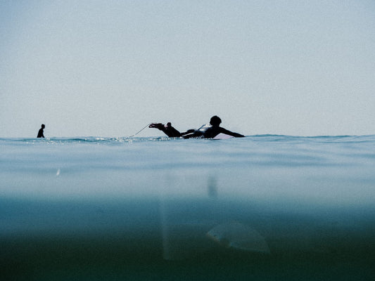 Surfista remando sobre su tabla en aguas frías, técnica de remada en olas de invierno.