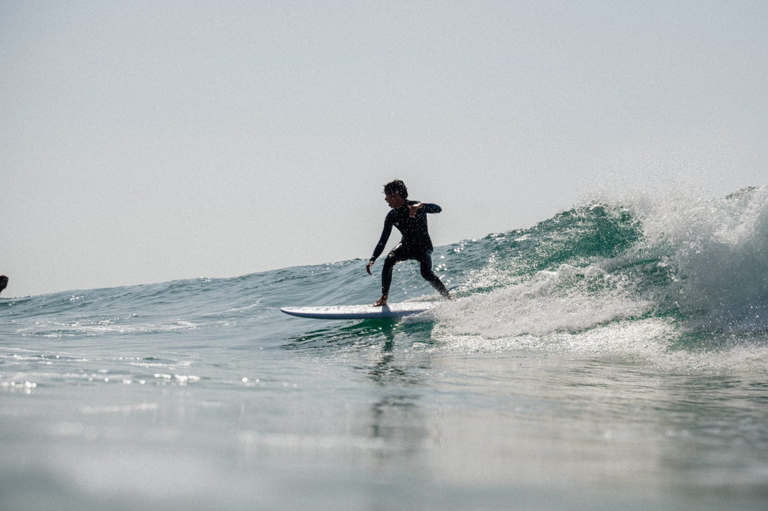 Surfista manteniendo el equilibrio sobre una ola durante una sesión de surf en el mar y sabe Manejar la frustración en el surf