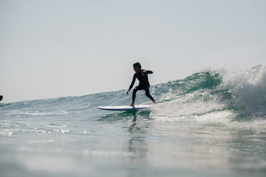 Surfista manteniendo el equilibrio sobre una ola durante una sesión de surf en el mar y sabe Manejar la frustración en el surf