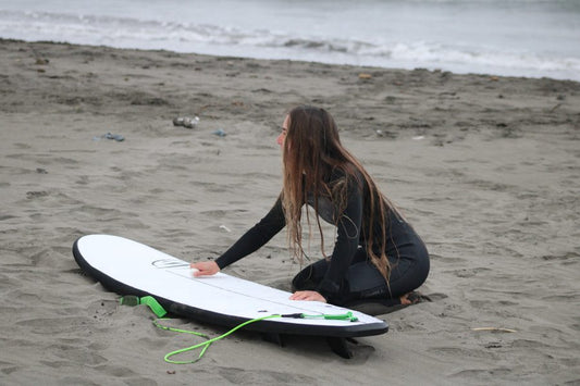 Mujer surfista con el neopreno y una tabla de surf evolutiva de Flysurf en invierno
