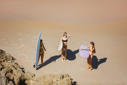 Tres surfistas con sus tablas de surf intermedia en la playa, listas para entrar al mar.