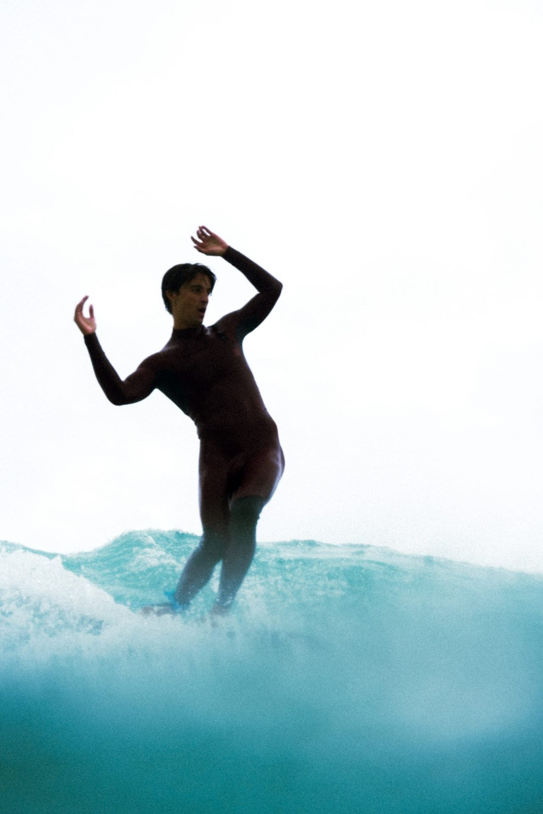 Surfista principiante remando sobre su tabla en una ola pequeña