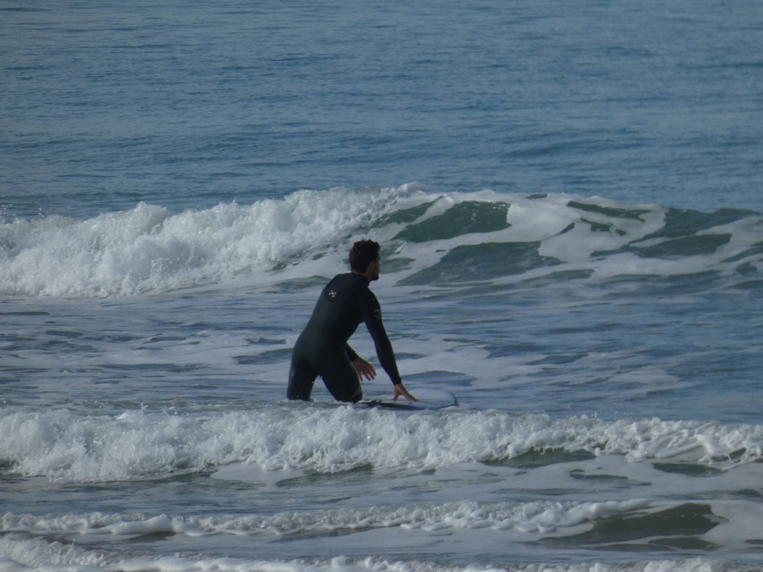Surfista en el agua con neopreno en una de las mejores playas de surf para otoño