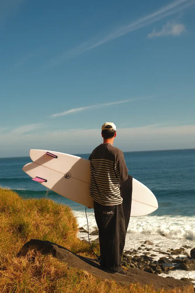 Alex mirando las olas de Madeira con la tabla de surf de fly fish blanca 6.4