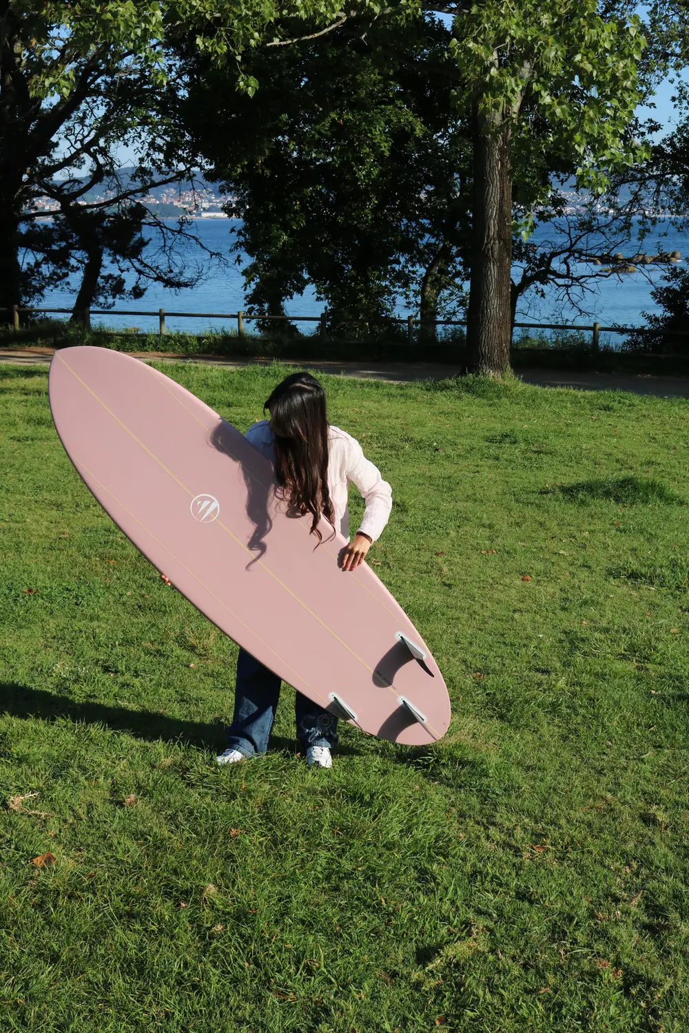 Antía con la tabla de surf de fibra flight mode rosa por la parte de detrás. 