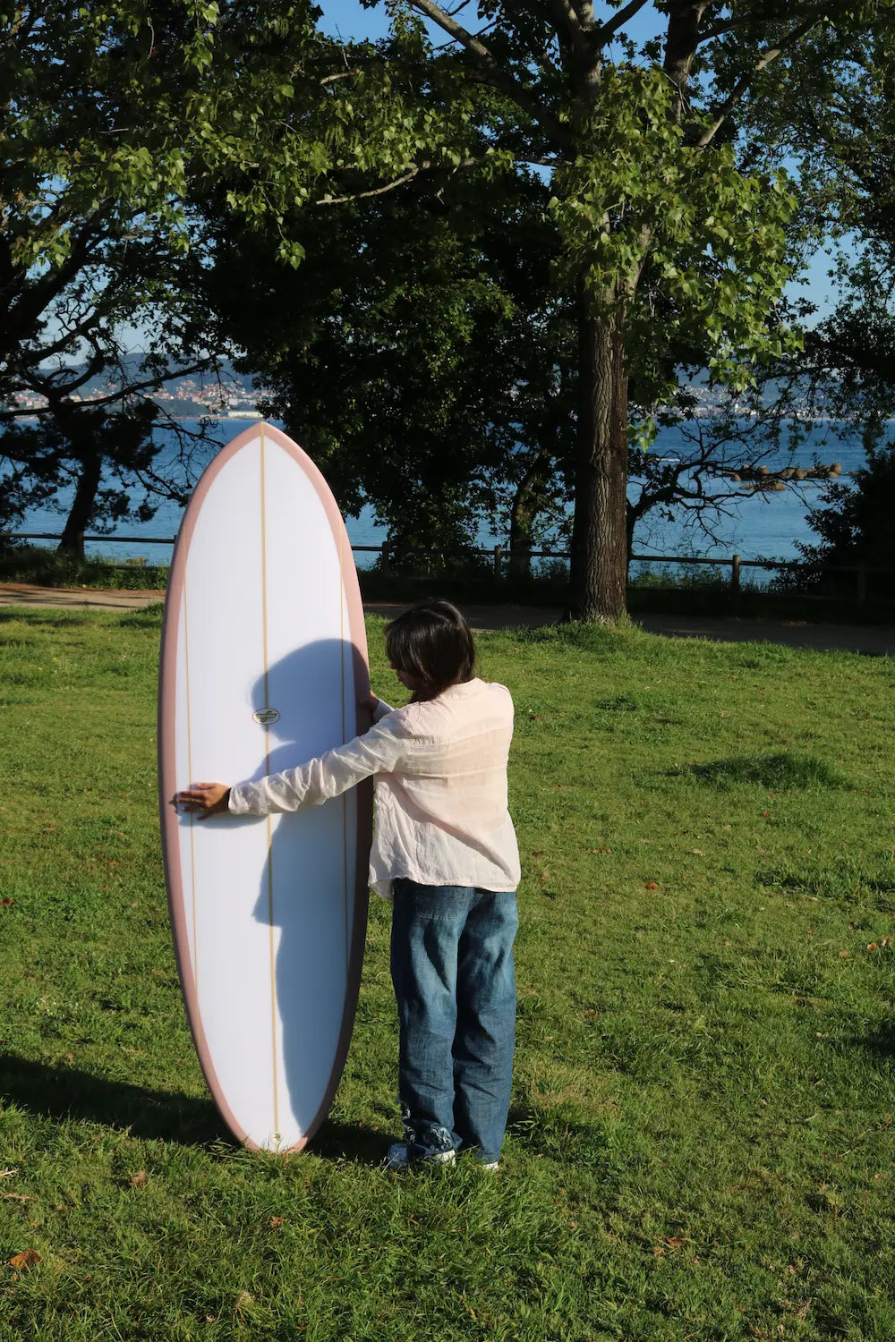 Antía con la tabla de surf de fibra funboard flight mode rosa sujetándola por delante. 