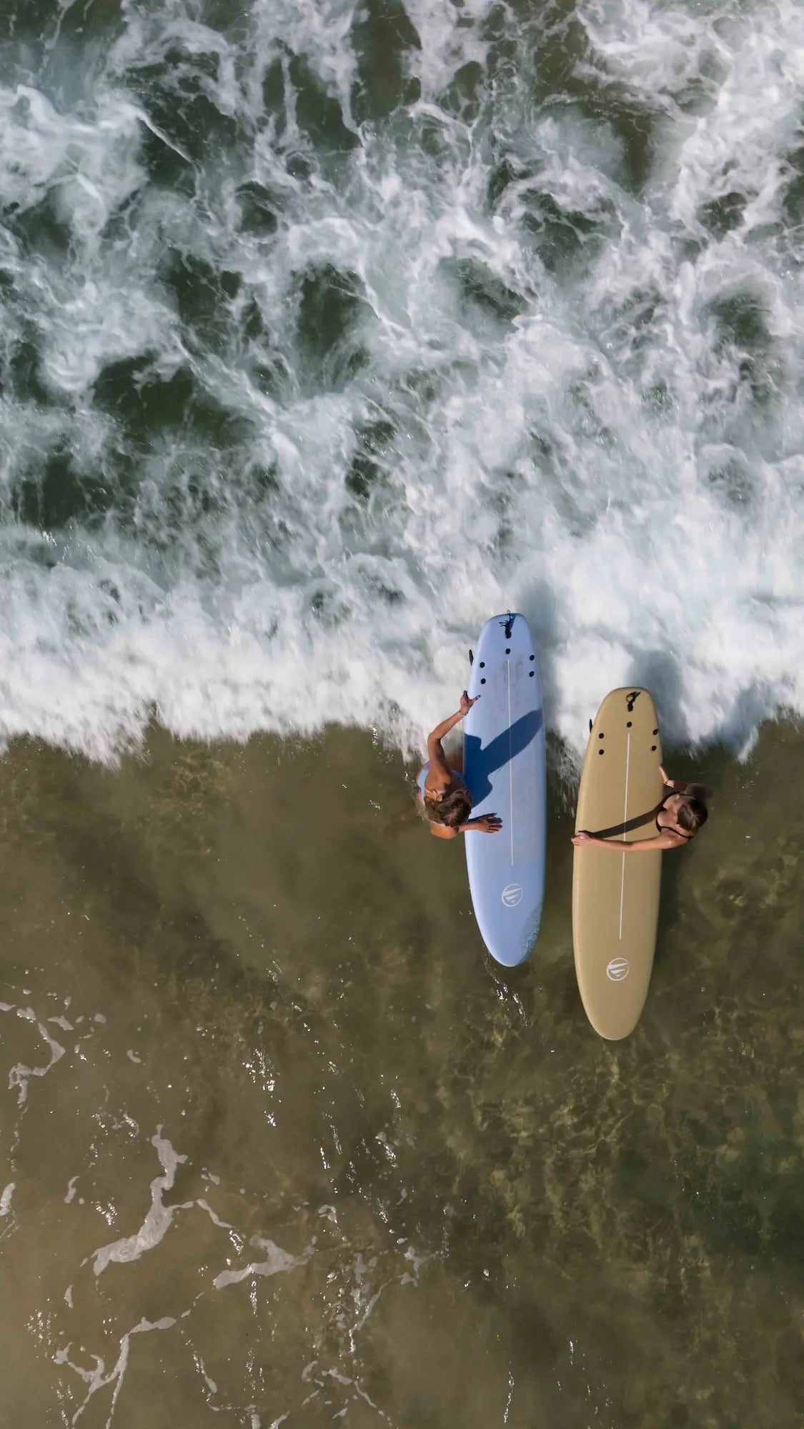 Surfeando en las espumas con las dos tablas de principiante de corcho. 