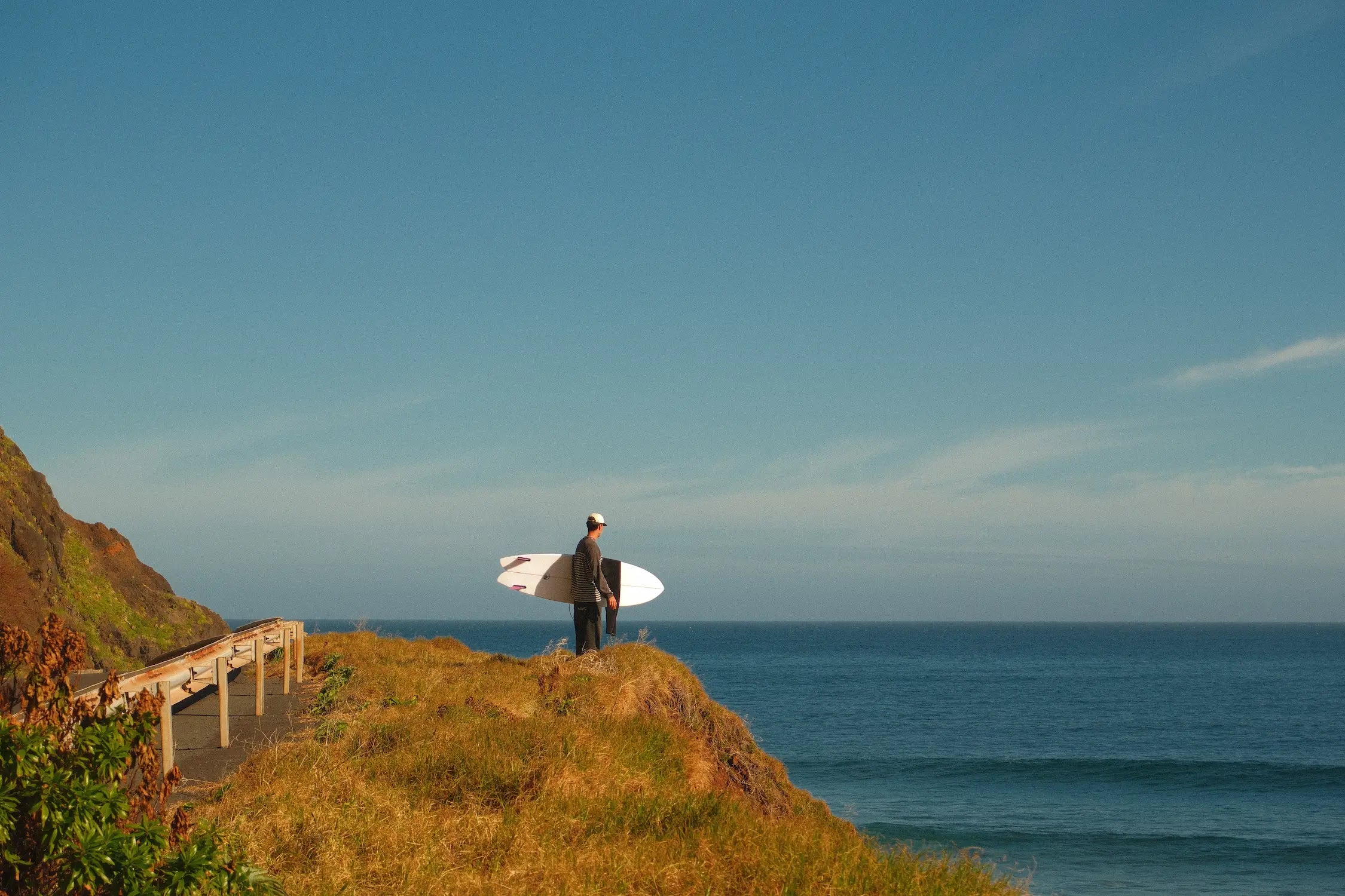 Alex mirando al mar con la tabla de surf de flysurf fish 6.4 blanca. 