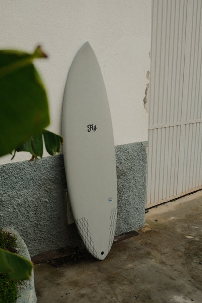 tabla de surf apollo gris de fibra de flysurf primer plano apoyada sobre la pared
