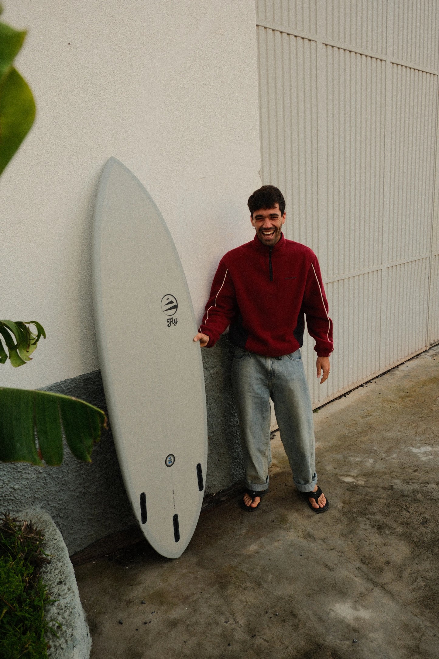 chico sonriendo y sosteniendo una tabla de surf de fibra de flysurf