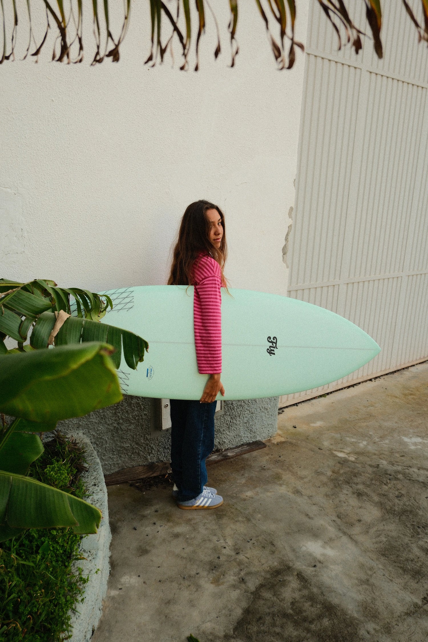 chica sosteniendo la tabla de surf de fibra color verde apollo 