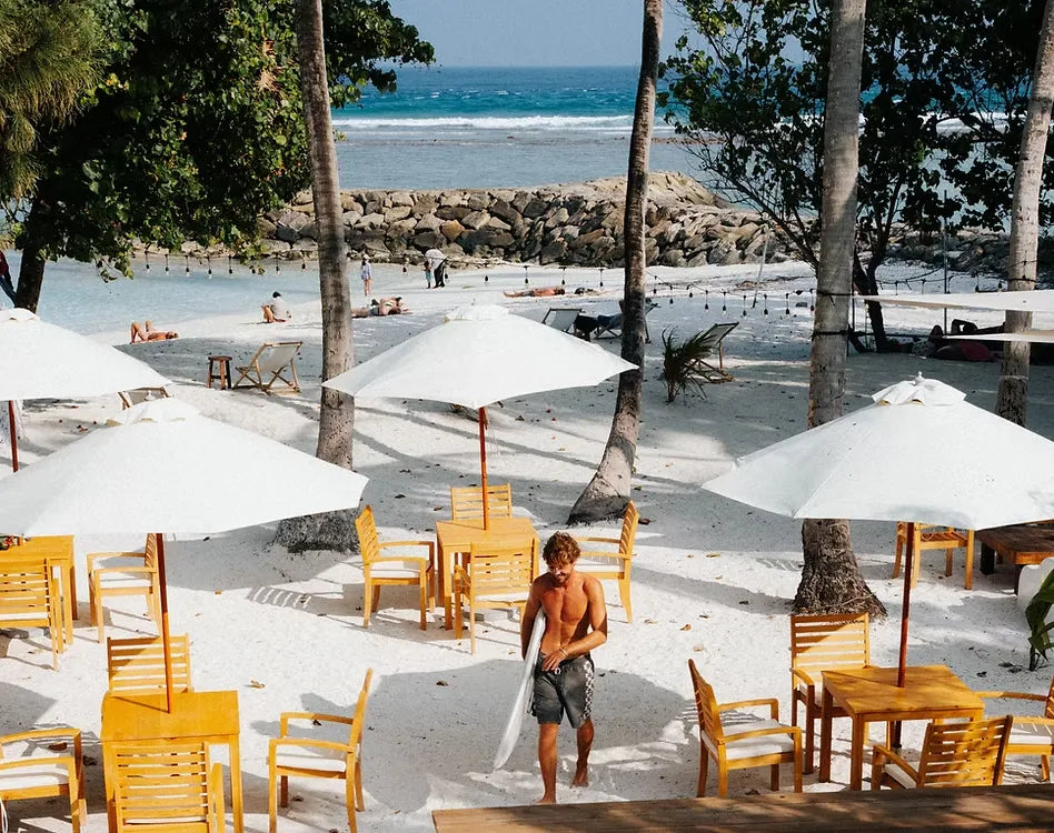 Zona de relax en la playa con sombrillas blancas y palmeras frente al mar