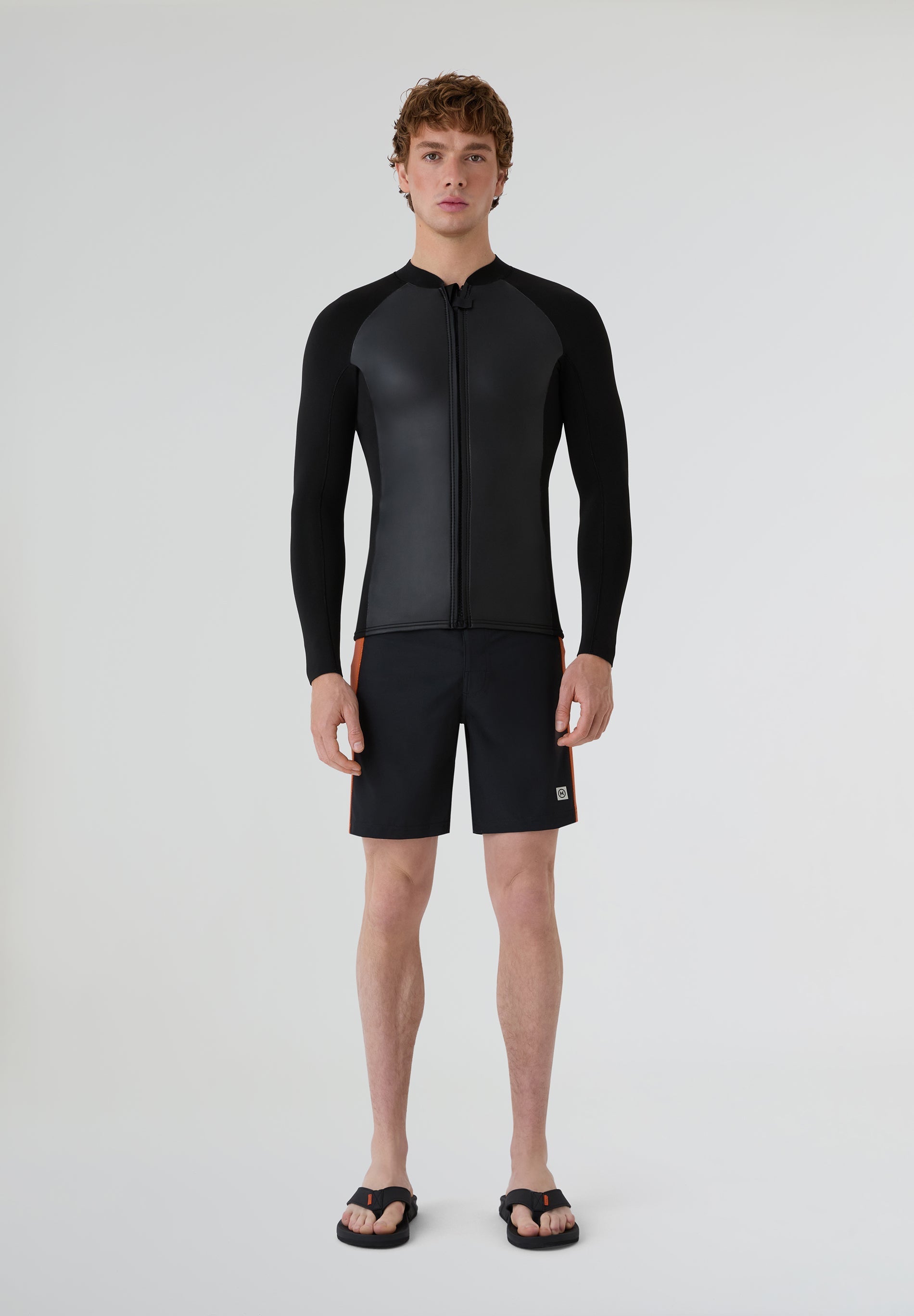 Modelo masculino vistiendo la camiseta de neopreno de 2mm combinada con bañador para sesiones de verano.
