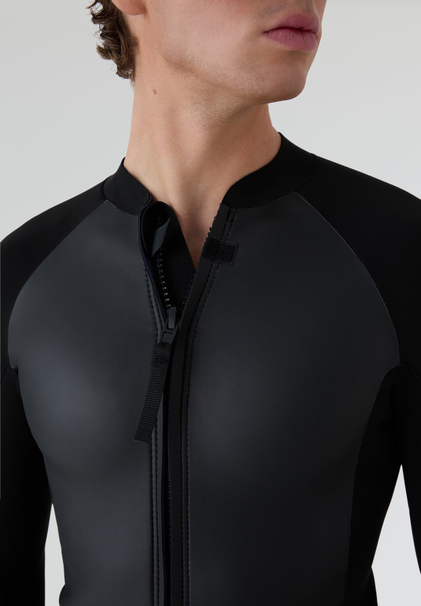 Detalle de la camiseta de neopreno con la cremallera semiabierta, resaltando la flexibilidad del material de 2mm.