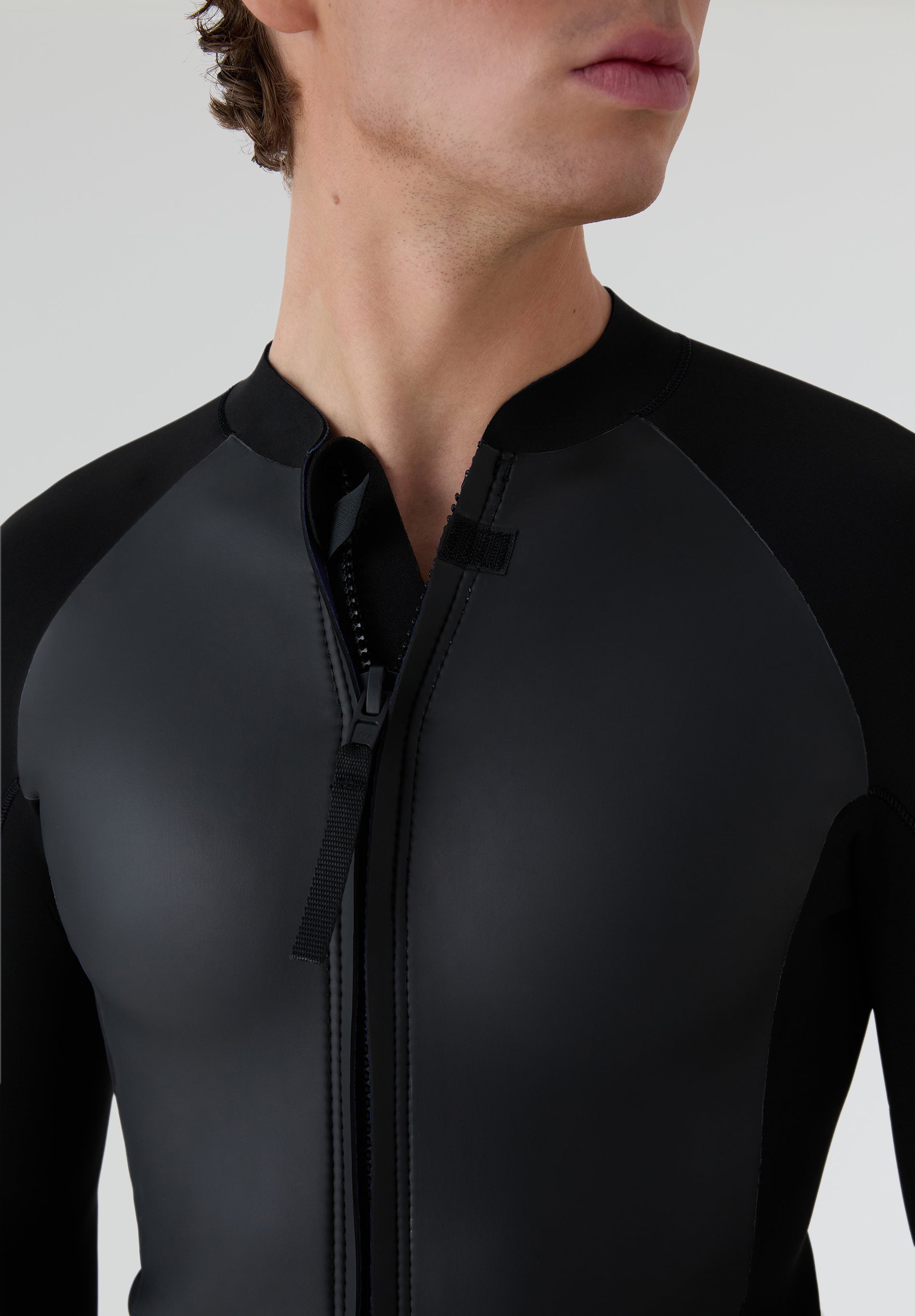 Detalle de la camiseta de neopreno con la cremallera semiabierta, resaltando la flexibilidad del material de 2mm.