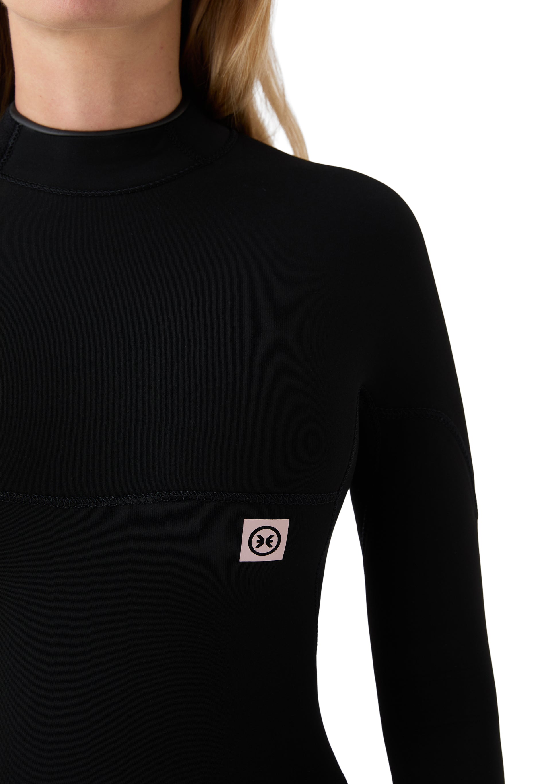 Primer plano del acabado del cuello y el parche distintivo de la serie Explorer en el pecho sobre neopreno negro.