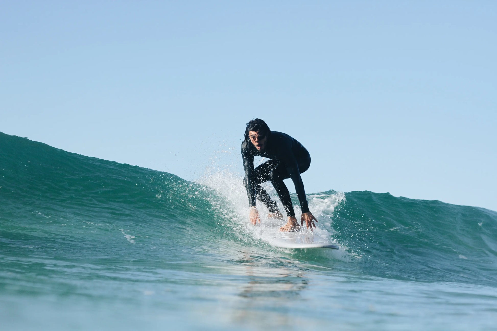 Hombre con traje de neopreno surfeando una ola con una tabla de surf epoxy de 7.2 pies.