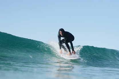 Hombre con traje de neopreno surfeando una ola con una tabla de surf epoxy de 7.2 pies.
