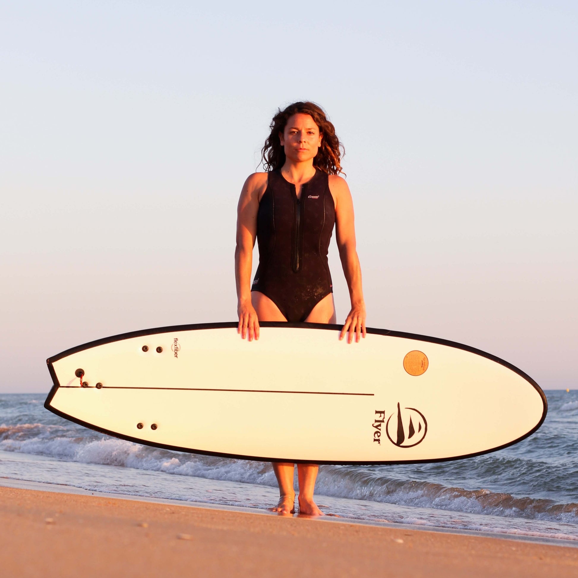 Mujer influencer con la tabla evolutiva The Traveller 6.6 en la playa