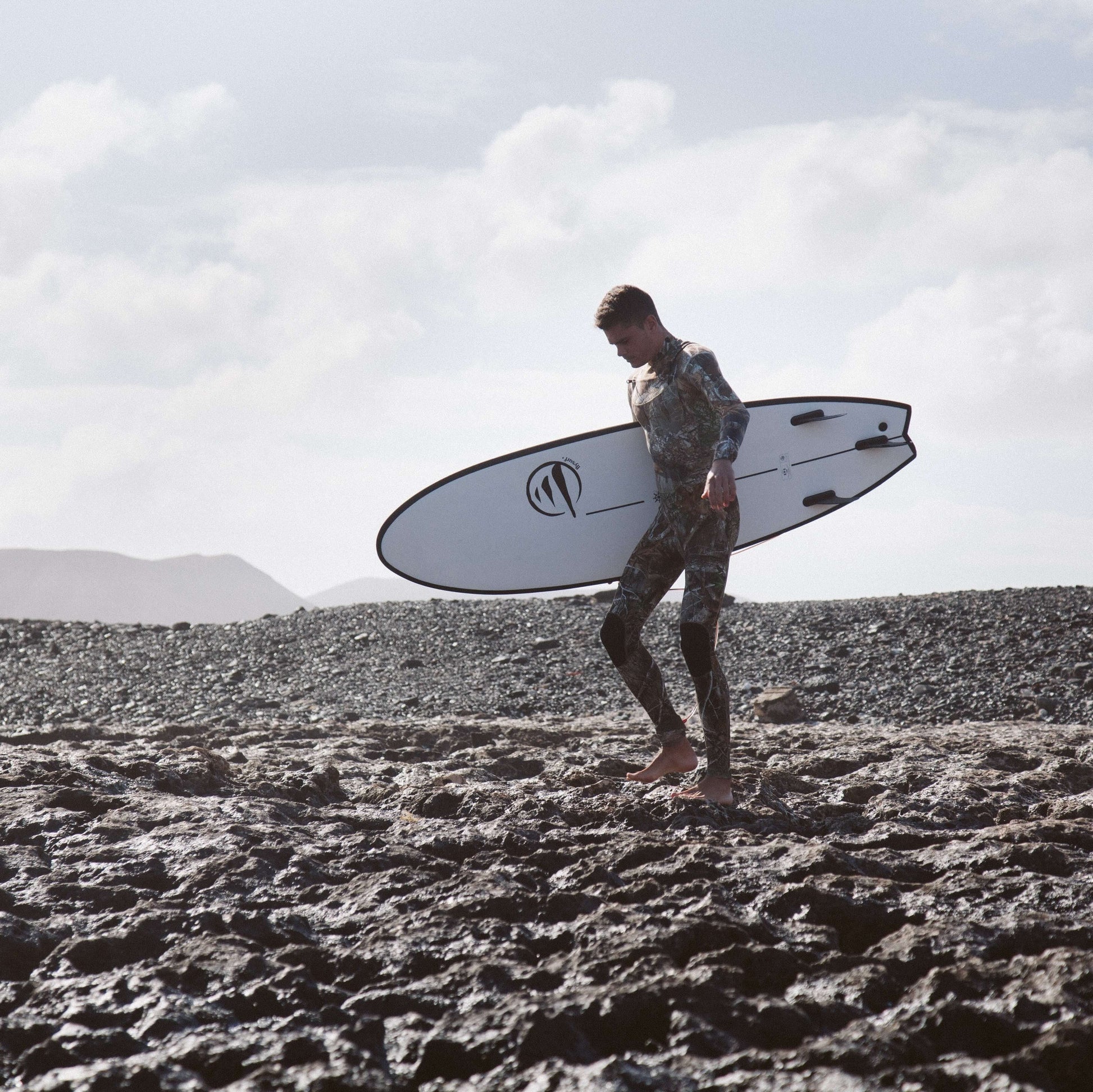 influencer andando por la playa con la tabla de surf evolutiva the traveller