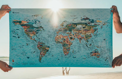 Mapa de surf del mundo ilustrado a mano sujetado en la playa al atardecer