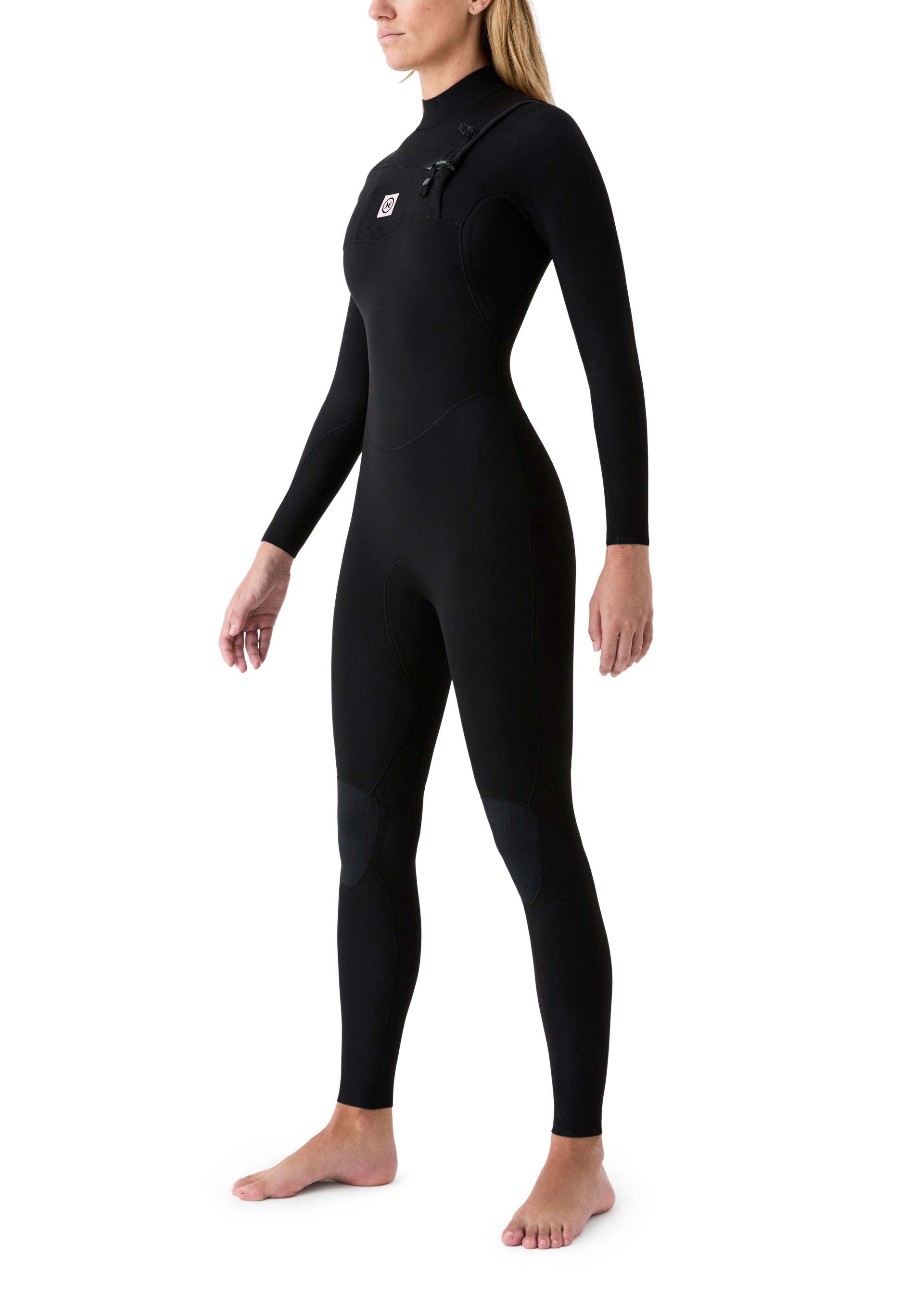 Vista lateral de una surfista usando el neopreno, resaltando el diseño de las mangas para una remada sin restricciones.
