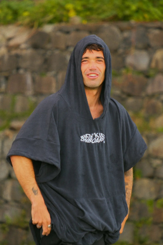 Alex en madeira cambiándose y poniéndose el neopreno con el poncho negro de surf. 