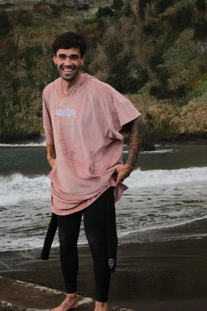 Alex poniéndose el neopreno con el poncho de surf rosa. 