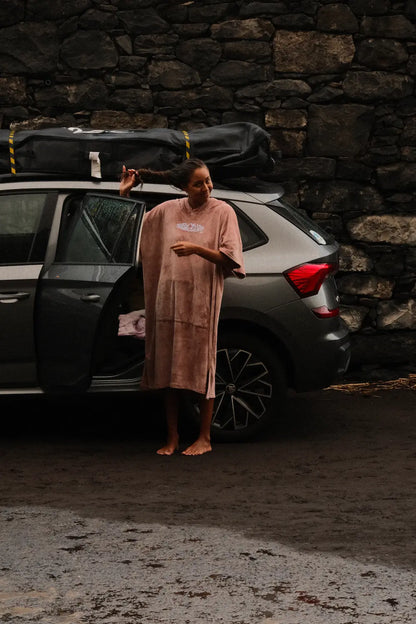 Guida cambiándose el neopreno al lado del coche con el poncho rosa. 