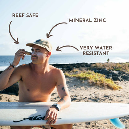 Surfista aplicándose protector solar de zinc en la cara antes de entrar al agua.