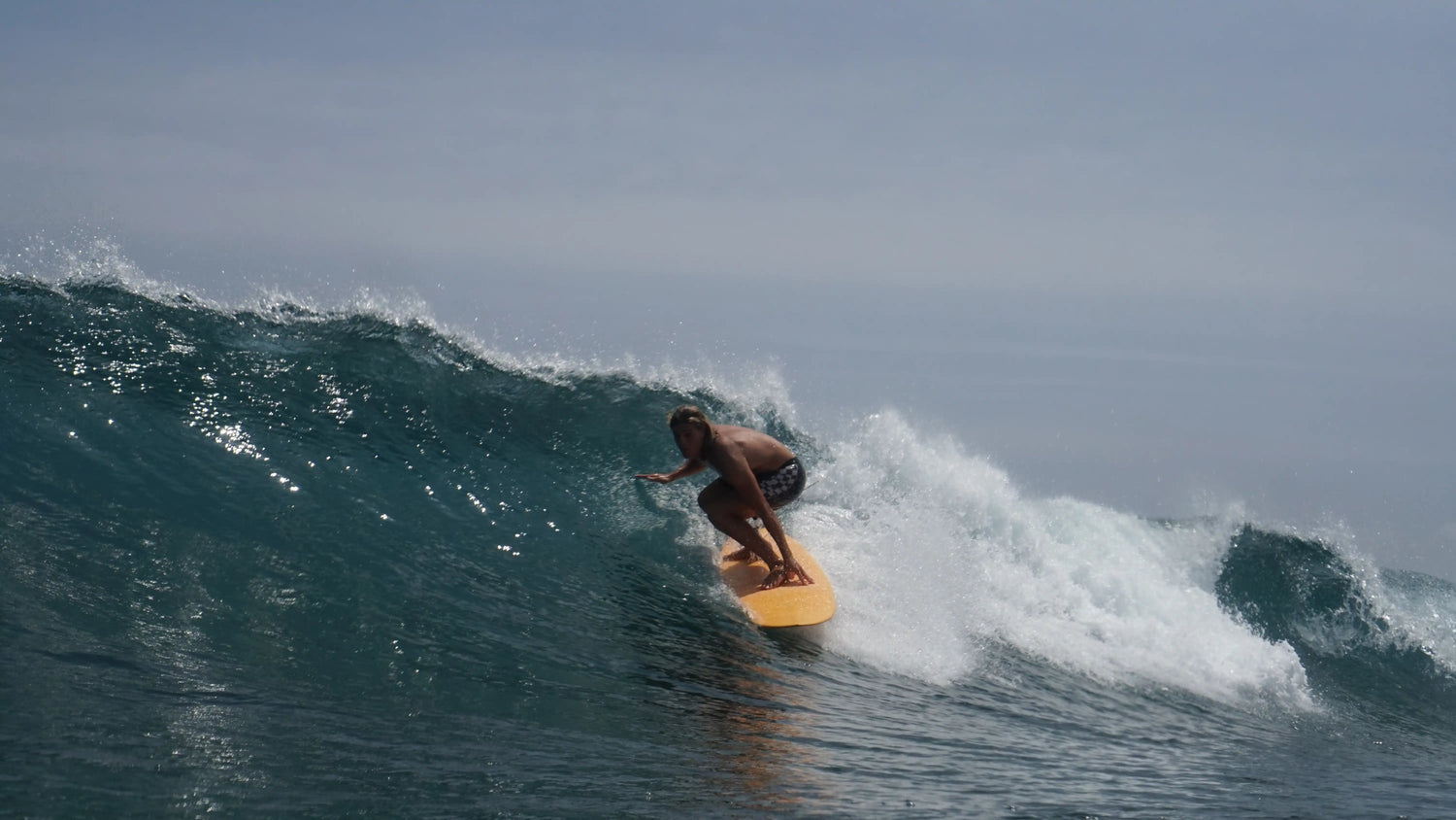 Surfista profesional bajando una ola rápida y perfecta en un arrecife de Maldivas.