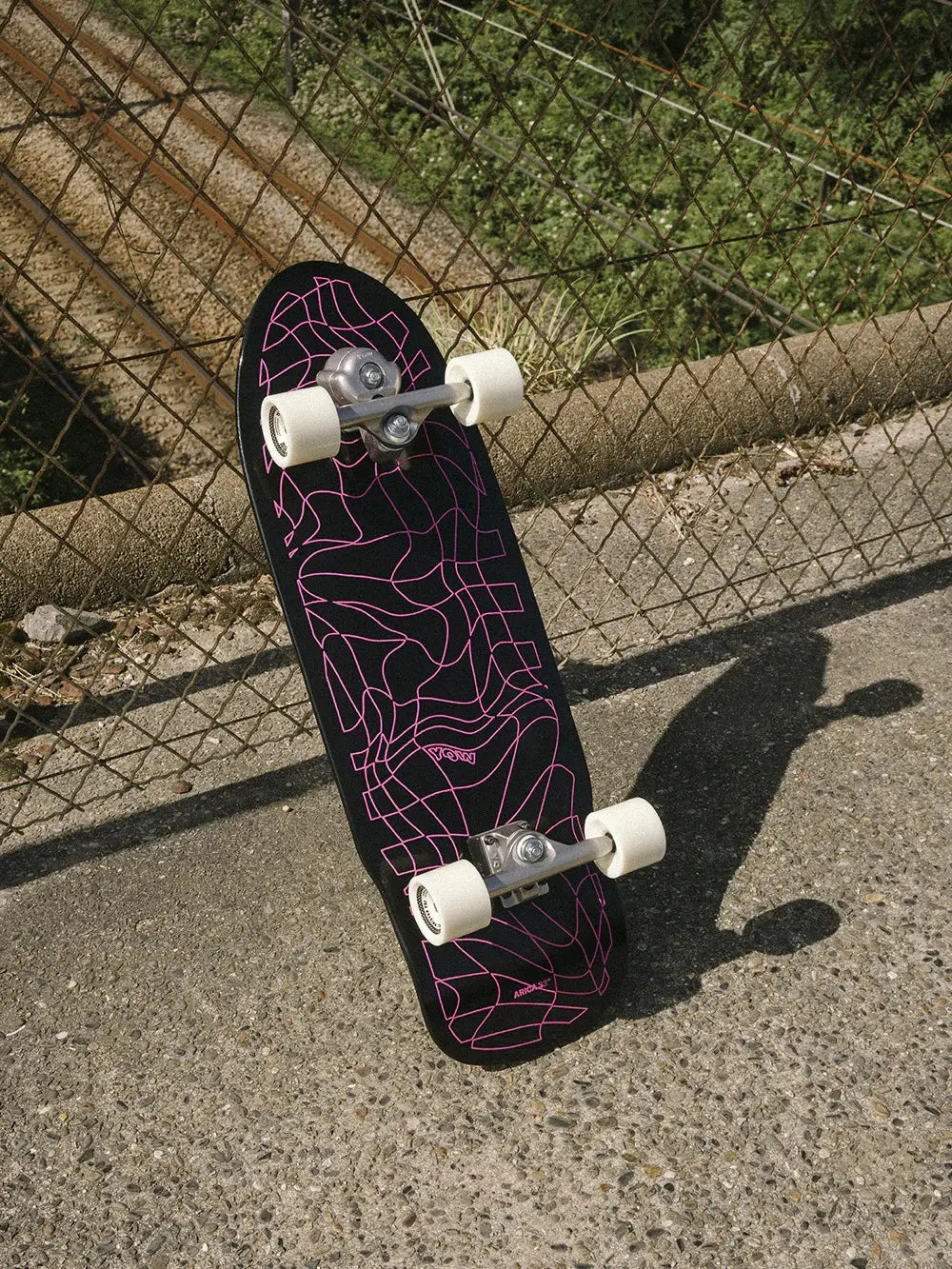 Surfskate YOW Arica 33 de la serie High Performance apoyado en el exterior para entrenamiento de surf en seco