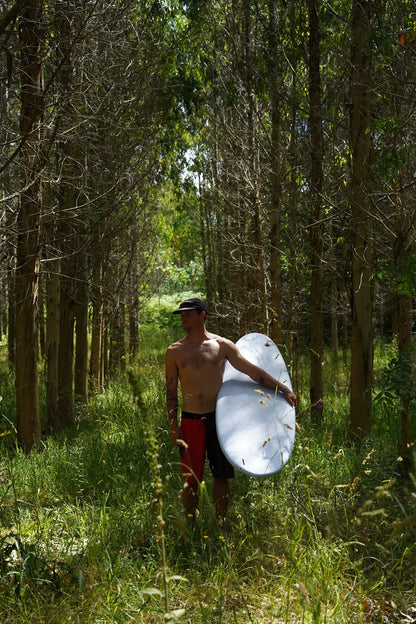 Chico caminando por el bosque con su tabla de surf Do It Your Wave - Flysurf