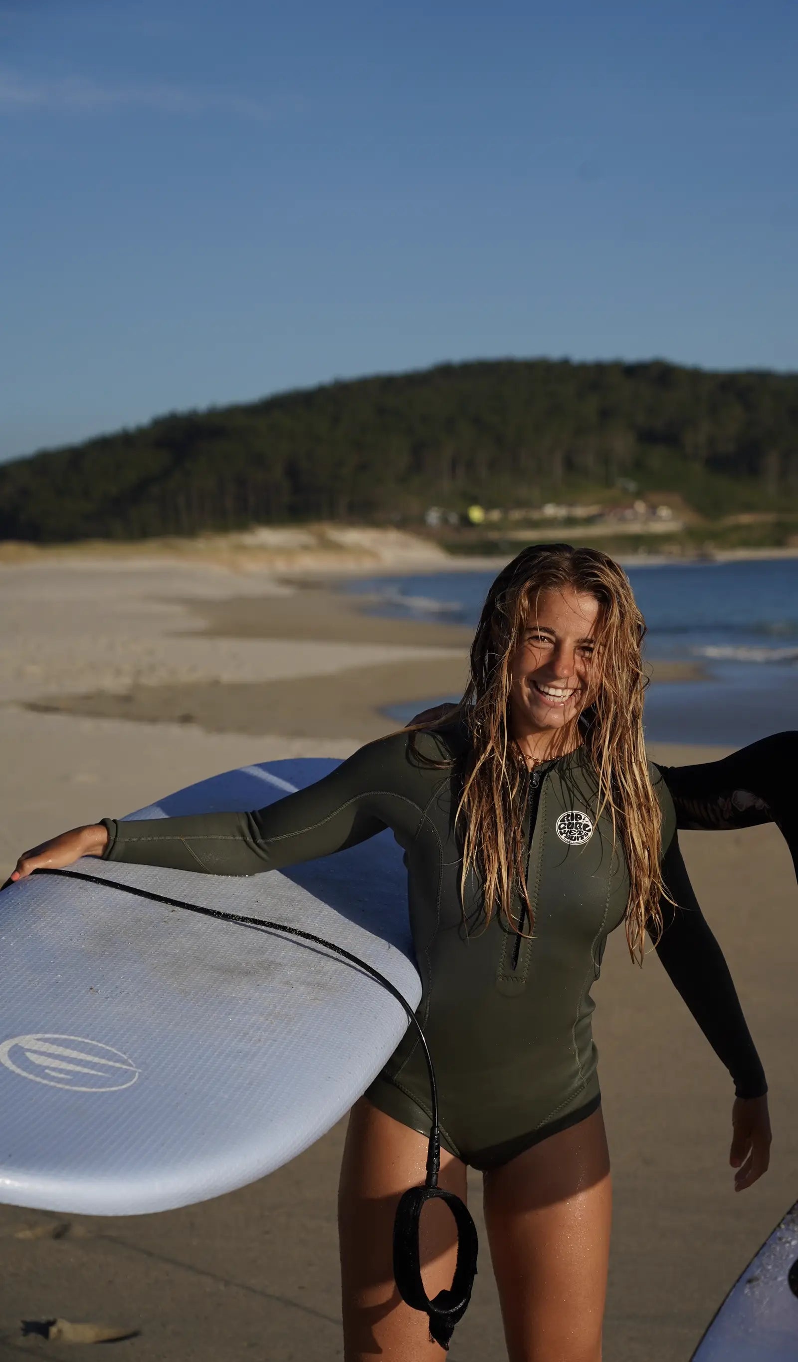 Chica sonriendo en la playa con su tabla de surf Do It Your Wave - Flysurf