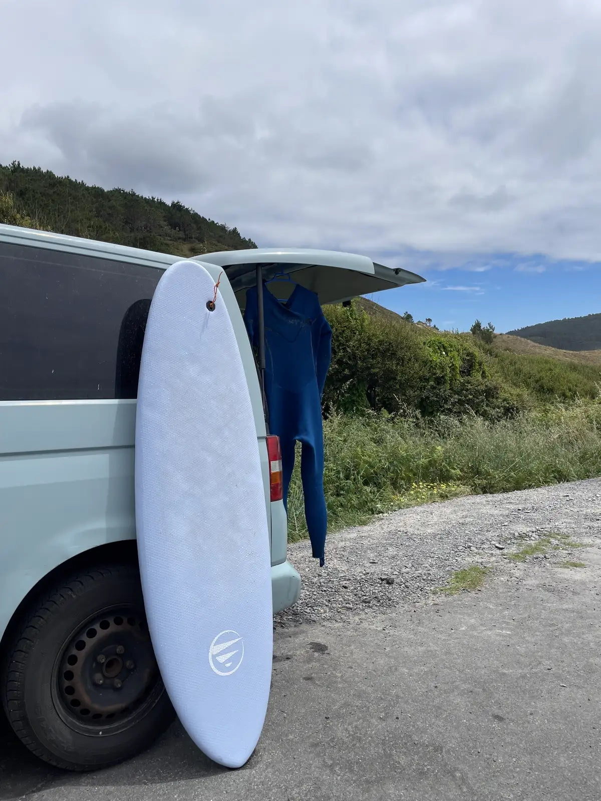 Tabla de surf Do It Your Wave apoyada en la furgoneta - Flysurf