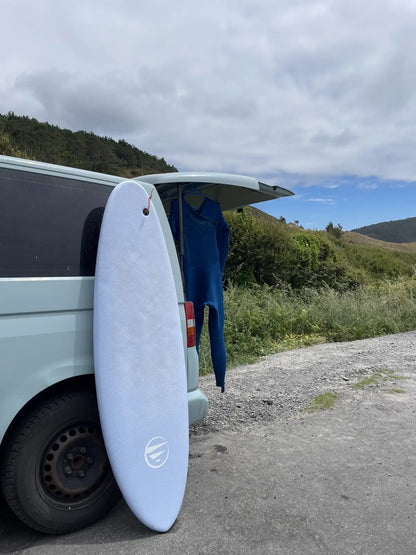 Tabla de surf Do It Your Wave apoyada en la furgoneta - Flysurf