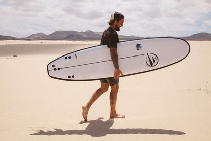 Influencer andando por la playa con una tabla de surf evolutiva de flysurf